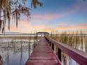 Wooden dock extending over calm lake water at sunset at 6320 Rocky Point Rd, Lake Wales, FL 33898