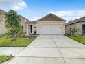 New single-story home with a two-car garage, simple landscaping, and a wide driveway under a blue sky at 791 Chinoy Rd, Davenport, FL 33837