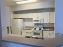 Functional kitchen with white appliances and cabinetry providing a bright and clean space at 5542 Metrowest Blvd # 206, Orlando, FL 32811