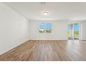 Spacious living room with sleek wood-look floors, a large window, and sliding glass doors to the patio at 1124 Griffon Ave, Lake Alfred, FL 33850