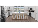 Bright kitchen boasts a large island with bar seating, stainless appliances, and white cabinets for a clean modern look at 12608 Ne 49Th Dr, Oxford, FL 34484