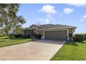 Exterior view of the home showcasing a well-maintained lawn, driveway, and attached two-car garage at 27601 Country Stone Ct, Leesburg, FL 34748