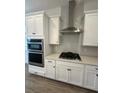 Modern kitchen features white cabinets, gas cooktop, and stainless steel range hood at 2817 Willowseed Ln, Saint Cloud, FL 34772