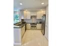 Well-lit kitchen with stainless steel appliances, granite countertops, and white cabinetry at 7652 Whisper Way # 104, Reunion, FL 34747