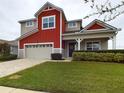 Two-story red and beige house with a gray paved driveway and landscaped lawn at 2506 Volunteer Ave, Kissimmee, FL 34744