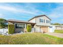 Two-story house with a large wooden garage door, landscaping, and a white picket fence at 610 Alton Rd, Winter Springs, FL 32708