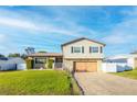 Two-story house with a large wooden garage door, landscaping, and a white picket fence at 610 Alton Rd, Winter Springs, FL 32708