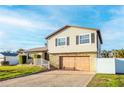 Two-story house with a large wooden garage door, landscaping, and a white picket fence at 610 Alton Rd, Winter Springs, FL 32708