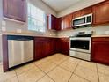 Well-equipped kitchen with stainless steel appliances and rich wood cabinetry at 7128 Five Oaks Dr, Harmony, FL 34773