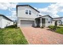 Attractive home boasts a brick driveway, attached garage, and manicured lawn with shrubbery at 2949 Wild Olive Dr, St Cloud, FL 34772