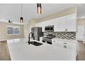Modern kitchen boasts white cabinets, stainless steel appliances, quartz counters, and designer backsplash at 139 Malauka Pass, Ocklawaha, FL 32179