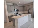 Modern kitchen featuring stainless steel appliances, gray cabinets, and an island at 2059 Town Pasture Dr, Eustis, FL 32726