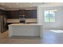 Bright kitchen with a central island, stainless steel appliances, and dark wooden cabinets at 2063 Town Pasture Dr, Eustis, FL 32726