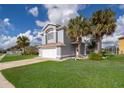 Inviting two-story home featuring an attached garage, verdant lawn, and mature palm trees at 3279 Fairfield Dr, Kissimmee, FL 34743
