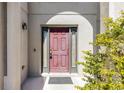 Close-up view of a stately, red front door framed by sidelights and elegant exterior lighting at 1907 Lakeview Way, Kissimmee, FL 34759
