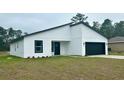 Modern home featuring a black garage door, window frames, white siding, and minimalist landscaping at 559 Marion Oaks Blvd, Ocala, FL 34473