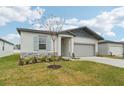 New construction home with gray siding, light stone accents, and a two-car garage at 2121 Rosewood Dr, Bartow, FL 33830