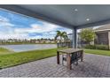 Covered patio with brick flooring features outdoor seating overlooking a serene lake and community landscape at 15155 Mayberry Dr, Winter Garden, FL 34787