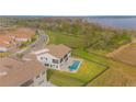 Aerial shot of a luxurious two-story home with a pool, manicured lawn, and expansive backyard with lake views at 13779 Abberwick Dr, Orlando, FL 32832