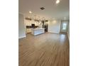 Open concept kitchen with island and light wood floors at 3185 Songbird Cir, Harmony, FL 34773
