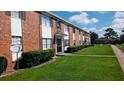 Red brick apartment building with black shutters, green lawn, and sidewalk under blue sky at 5317 Curry Ford Rd # J101, Orlando, FL 32812