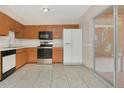 Galley kitchen with wood cabinets, stainless steel appliances, and tiled floor at 113 Kristi Ann Ct # 113, Winter Springs, FL 32708