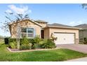 Tan single story house with landscaping and a two-car garage at 17833 Blazing Star Cir, Clermont, FL 34714