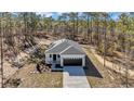 Aerial view of charming single-story home featuring a white exterior, dark garage door, and a well-manicured lawn surrounded by trees at 406 Nw Narcissus Rd, Dunnellon, FL 34431