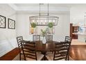 Formal dining room with a round wooden table and six chairs, hardwood floors and a modern chandelier at 483 Douglas Edward Dr, Ocoee, FL 34761