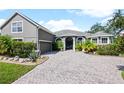 Two-story house with gray siding, paver driveway and landscaping at 1424 Richmond Grand Ave, Orlando, FL 32820