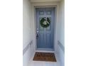 Charming blue front door adorned with a wreath and welcome mat at 1656 Aspen Ave, Davenport, FL 33837