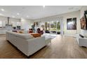 Bright, open-concept living room featuring wood floors, a large sectional, and sliding glass doors to the backyard at 4223 Sunset Preserve Blvd, Orlando, FL 32820