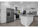 Modern kitchen features stainless steel appliances, a granite countertop island, and wood-look tile floors at 1208 Old Apopka Rd, Apopka, FL 32703