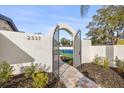 Arched gate entrance leading to the tennis court, showcasing well-maintained landscaping and attractive brick pathway at 2337 Worthington Rd, Maitland, FL 32751