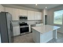 Modern kitchen with white cabinets, stainless steel appliances, and an island at 3207 Laurent Loop, Davenport, FL 33837