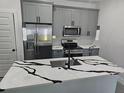 Modern kitchen featuring grey cabinets, stainless steel appliances, and island with quartz counters at 0 Robinson Dr, Haines City, FL 33844