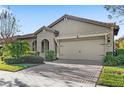 One-story home with a neutral color scheme, attractive landscaping, and a brick driveway at 10713 Berry Creek Rd, Orlando, FL 32836