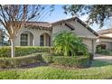 Well-maintained house with lush landscaping, arched entryway, and a terracotta tile roof at 10713 Berry Creek Rd, Orlando, FL 32836
