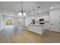 Bright, open-concept living space features wood floors, sliding glass doors, kitchen island, and modern light fixtures at 14962 Sw 39Th Cir, Ocala, FL 34473