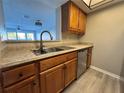 Kitchen with wood cabinets, granite counters, and stainless steel dishwasher at 5775 Peregrine Ave # D03, Orlando, FL 32819