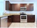 Kitchen with dark wood cabinets, granite countertops, and stainless steel appliances at 1824 Palmetto Scrub Cir, Port Orange, FL 32128