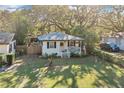 Quaint white cottage with a lush green yard and surrounding trees at 805 E 20Th St, Sanford, FL 32771