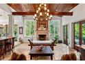 Elegant living room with wood-beamed ceiling, stone fireplace, tile flooring, and abundant natural light from large windows at 1426 Nottingham St, Orlando, FL 32803