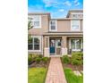 Tan two-story townhome with blue door, brick walkway, and landscaping at 8127 Cadman St, Orlando, FL 32832