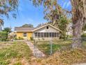 Quaint one-story home with a fenced yard and a large tree in the front yard at 201 N East St, Leesburg, FL 34748