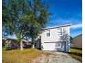 Two-story house with a two-car garage and mature tree in the front yard at 266 Vervain Ave, Davenport, FL 33837