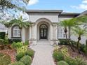 Elegant home featuring manicured landscaping, a stone walkway and a covered entrance with decorative columns at 4520 Old Carriage Trl, Oviedo, FL 32765