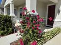 Charming front entrance with a red door and lovely landscaping, including pink bougainvillea at 10249 Spring Lake Dr, Clermont, FL 34711