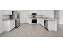 Bright, modern kitchen featuring stainless steel appliances, white cabinets, and stylish wood-look flooring at 4505 Hummingbird Ln, Haines City, FL 33844