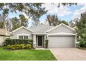 Gray house with a two-car garage and neatly landscaped front yard at 5813 Great Egret Dr, Sanford, FL 32773